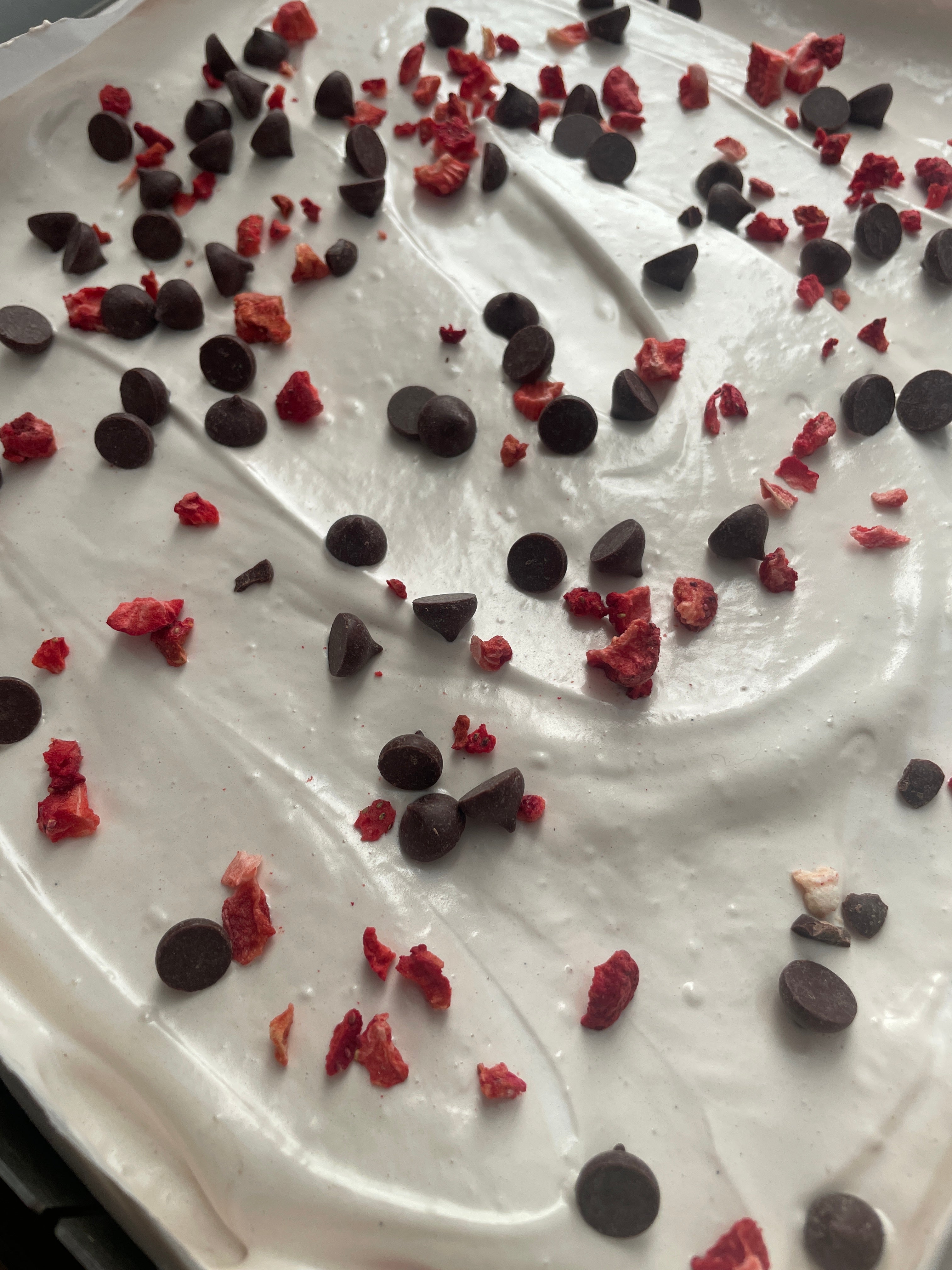 part of a sheet of strawberry and chocolate marshmallow decorated with chocolate chips and strawberry pieces